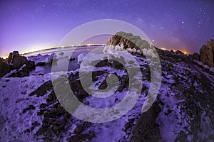 On winter nights, snow and ice cover the rocks by the sea