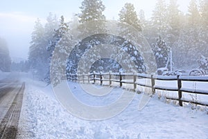 Winter old American Country landscape with rustic houses, cars and fences covered in snow
