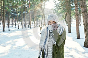 Winter outdoor portrait of of happy girl feeling cold and covering face with woolen scarf at snowly park
