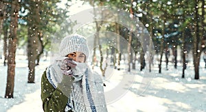 Winter outdoor portrait of of happy girl feeling cold and covering face with woolen scarf at snowly park