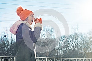 Winter outdoor portrait of young girl screaming in a megaphone paper cup, copy space