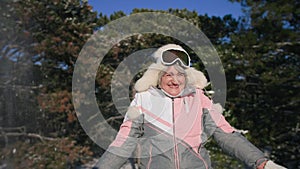 winter outdoor recreation, charming elderly woman in warm winter clothes shines snow in sunny weather while relaxing in
