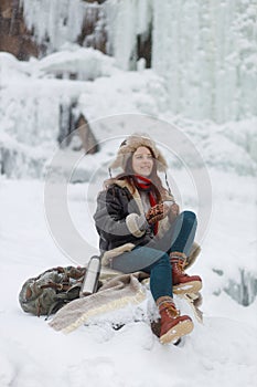 Winter outdoor recreation. Young woman drinks hot tea from thermos