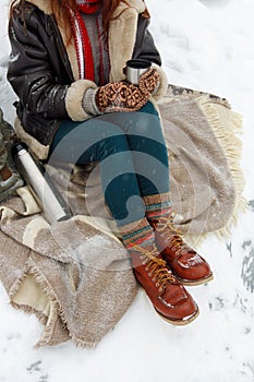 Winter outdoor recreation. Young woman drinks hot tea from thermos