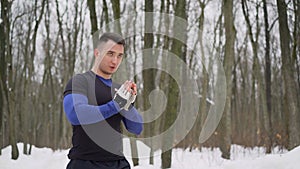 Winter outdoor workout concept. Cheerful mature guy doing warmup exercises before his run in snowy winter forest. The