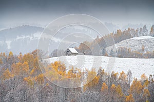 Winter over some beautiful authentic traditional villages in Romania with old houses and some autumn fall coloured trees in Rucar-