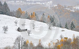 Winter over some beautiful authentic traditional villages in Romania with old houses and some autumn fall coloured trees in Rucar-