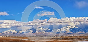 Winter Panoramic view of Snow capped Wasatch Front Rocky Mountains, Great Salt Lake Valley and Cloudscape from the Bacchus Highway