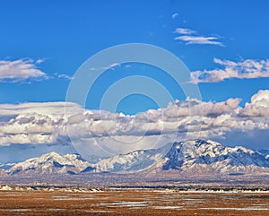 Winter Panoramic view of Snow capped Wasatch Front Rocky Mountains, Great Salt Lake Valley and Cloudscape from the Bacchus Highway