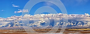 Winter Panoramic view of Snow capped Wasatch Front Rocky Mountains, Great Salt Lake Valley and Cloudscape from the Bacchus Highway