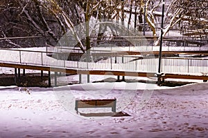 Winter park in the evening covered with snow with a row of lamps