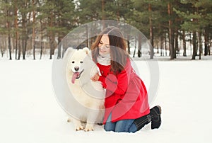 Winter and people concept - happy smiling young woman having fun with white Samoyed dog