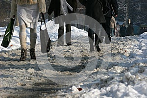 Winter. People walk on a very snowy sidewalk. People step on an snow-stray pathway. Icy sidewalk. Ice on sidewalks photo