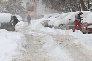 Winter. People walk on a very snowy sidewalk and road. People step on an icy pathway, icy sidewalk. Uncleaned streets and roads