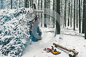 Winter picnic in forest with Christmas candles and fruits on wooden planks near bushcraft survival shelter