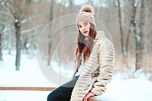 Winter portrait of beautiful young woman in fur coat and knitted hat