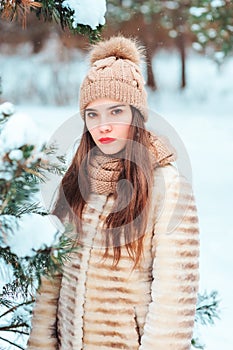 Winter portrait of beautiful young woman in fur coat and knitted hat