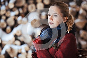 Winter portrait of blonde woman on firewood background