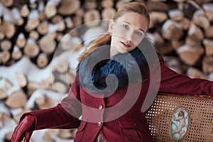 Winter portrait of blonde woman on firewood background