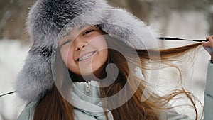 Winter portrait of a cheerful teenage girl in a fur hat