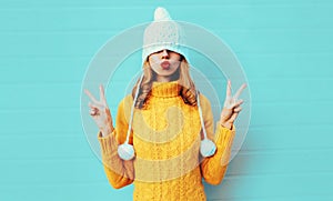 Winter portrait cool young woman having fun pulls a hat over her eyes wearing yellow knitted sweater and white hat with pom pom