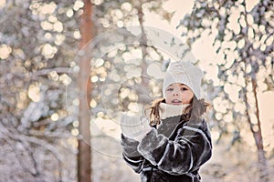 Winter portrait of cute child girl in fur coat on the walk in snowy forest