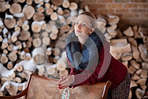 Winter portrait of the girl on a background firewood
