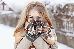 Winter portrait of a girl hiding in her scarf on the background