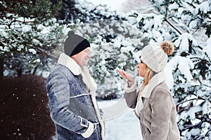 winter portrait of happy couple playing, blowing snow and spending good day outdoor