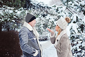 winter portrait of happy couple playing, blowing snow and spending good day outdoor in snowy forest