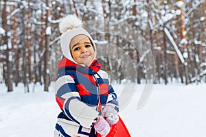 Winter portrait of happy little girl wearing knitted hat and a jumpsuit outdoor in winter