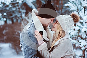 Winter portrait of happy romantic couple embracing and looking to each other outdoor in snowy day