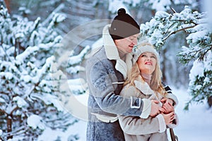 winter portrait of happy romantic couple enjoying their walk in snowy forest or park