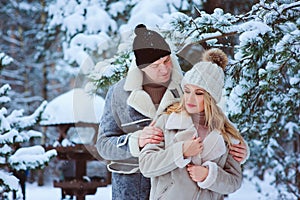 Winter portrait of happy romantic couple enjoying their walk in snowy forest or park