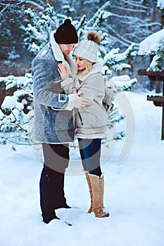 winter portrait of happy romantic couple warm up each other on the walk in snowy forest