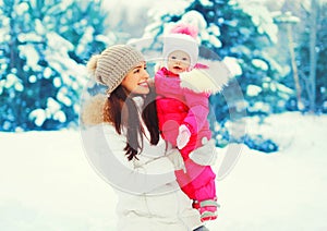 Winter portrait happy smiling mother with baby on her hands over snowy christmas tree