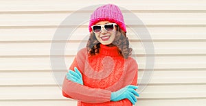 Winter portrait happy smiling young woman wearing a knitted sweater, pink hat having fun on white background