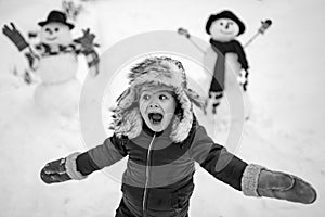 Winter portrait of little boy child in snow Garden make snowman. Child playing with Snowman on snow background. Winter