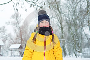 Winter portrait of little girl with pigtails in jacket and blue hat in winter