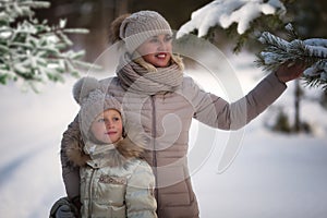 Winter portrait of mom and daughter. Merry mom and daughter. Two girls in winter. Cold season