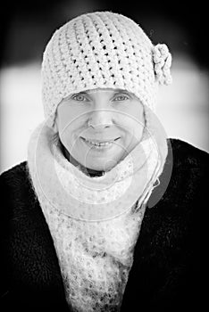 A winter portrait of a smiling senior adult woman wearing a wool cap and a scarf