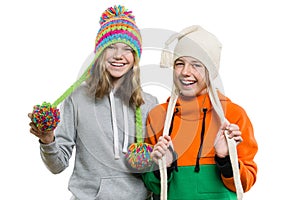 Winter portrait of two happy smiling pretty girls in knitted hats having fun, isolated on white background, people, youth and frie