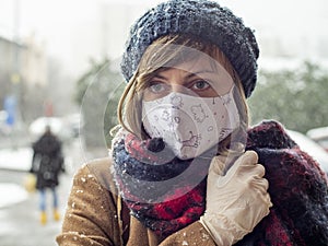 Winter portrait of woman on street wearing protective face mask and gloves