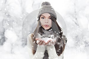 Winter portrait. Young, beautiful woman blowing snow photo