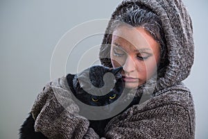 Winter portrait of young kind woman holding big black cat