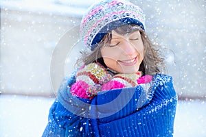 Winter portrait of a young woman. Beauty Joyous Model Girl touching her face skin and laughing, having fun in the winter park. Bea