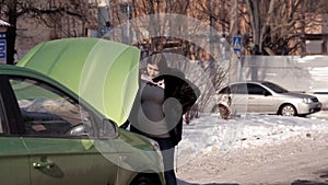 In winter, a pregnant girl is looking for help from passing cars in the repair of a failed car