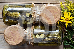 Winter preservation: pickled cucumbers with coriander in glass jars on a wooden table. Top view