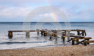 Winter rainbow seascape of Baltic sea with vintage jetty platform over beach of Gdynia Orlowo district of Tricity in Poland