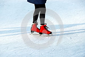 Winter rink. The girl in the red skates riding on the ice. Active family sport during the winter holidays and the cold season.